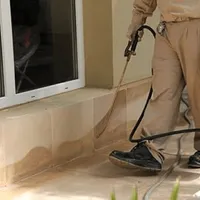 General pest control technician spraying exterior perimeter around a home in Anaheim, CA